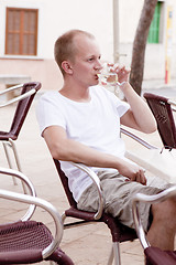 Image showing young man sitting outdoor in a cafe in summer