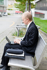 Image showing business man sitting outdoor working with notebook