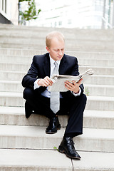 Image showing young business man is reading newspaper outdoor