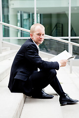 Image showing young business man is reading newspaper outdoor