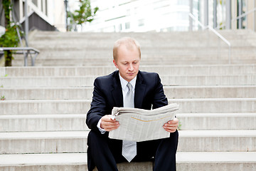 Image showing young business man is reading newspaper outdoor