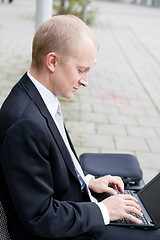 Image showing business man sitting outdoor working with notebook