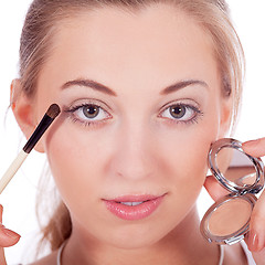 Image showing beautiful woman applying make up on face