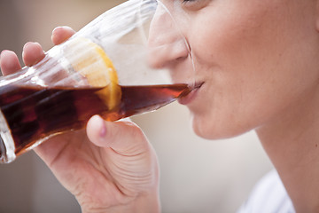 Image showing young woman is drinking lemonade outside in summer