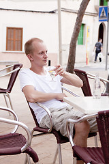 Image showing young man sitting outdoor in a cafe in summer