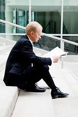 Image showing young business man is reading newspaper outdoor