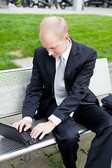 Image showing business man sitting outdoor working with notebook