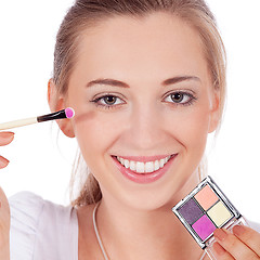 Image showing beautiful woman applying make up on face