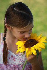 Image showing Young girl smelling a sunflower