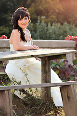 Image showing Girl in the wedding dress sitting on the bench