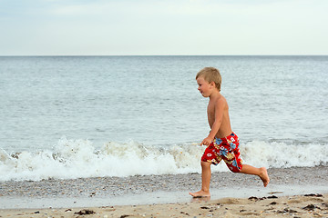 Image showing Little boy running at the seashore
