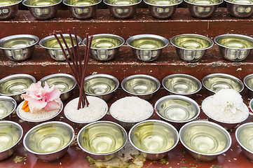 Image showing small bowls with water and rice around a temple