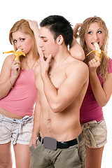 Image showing Young man and two playful women with bananas