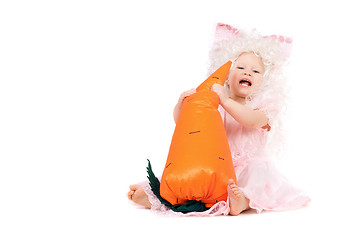 Image showing Happy baby girl plays with a carrot