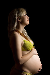 Image showing Happy pregnant young woman in yellow lingerie. Isolated