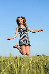 Image showing attractive girl jumping in field