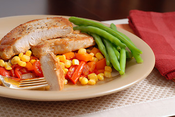 Image showing Plate of pork chops resting on a bed of corn, peppers and onions