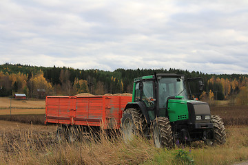 Image showing Green Tractor and Agricultural Trailer by Bean Field