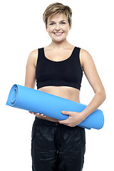 Image showing Health conscious woman holding blue exercise mat