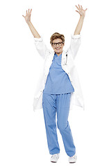 Image showing Cheerful doctor raising her hands up in celebration