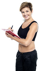 Image showing Female gym instructor writing diet chart