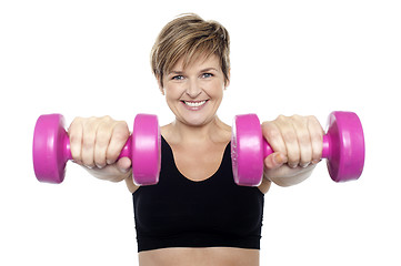 Image showing Lady holding pink dumbbells. Arms outstretched