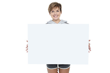 Image showing Charming young woman holding white ad board