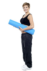 Image showing Smiling female instructor carrying a blue yoga mat