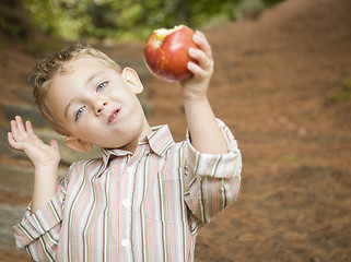 Image showing Adorable Child Boy Eating Red Apple Outside