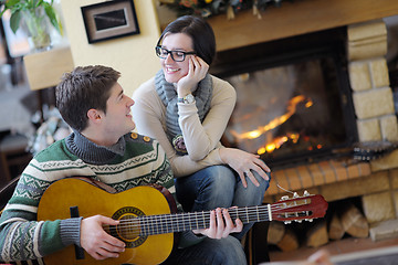 Image showing Young romantic couple sitting and relaxing in front of fireplace