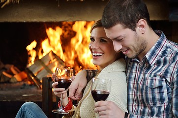 Image showing Young romantic couple sitting on sofa in front of fireplace at h