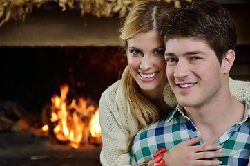 Image showing Young romantic couple sitting on sofa in front of fireplace at h