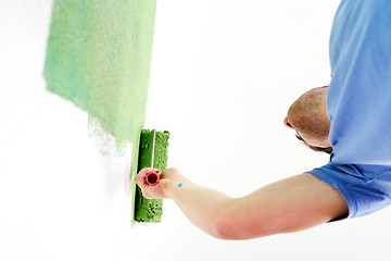 Image showing handsome young man paint white wall in color