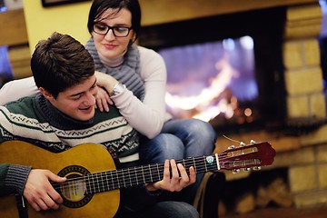 Image showing Young romantic couple relax on sofa in front of fireplace at hom