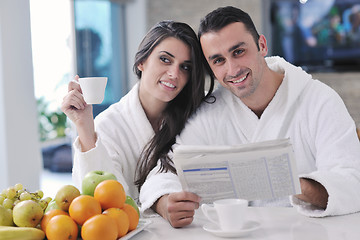 Image showing Happy couple reading the newspaper in the kitchen at breakfast