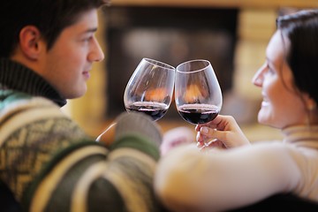 Image showing Young romantic couple sitting on sofa in front of fireplace at h