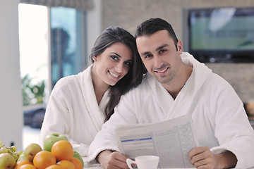 Image showing Happy couple reading the newspaper in the kitchen at breakfast