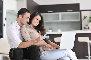 Image showing joyful couple relax and work on laptop computer at modern home