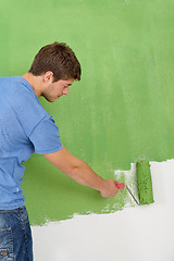 Image showing handsome young man paint white wall in color