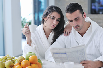 Image showing Happy couple reading the newspaper in the kitchen at breakfast