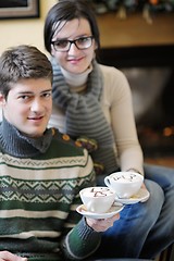 Image showing Young romantic couple sitting on sofa in front of fireplace at h