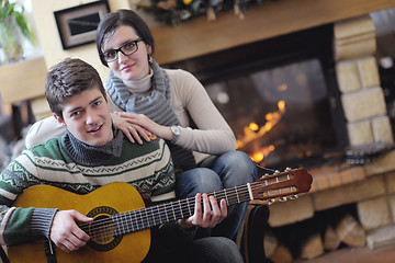 Image showing Young romantic couple sitting and relaxing in front of fireplace