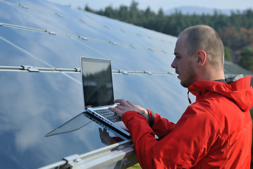 Image showing engineer using laptop at solar panels plant field