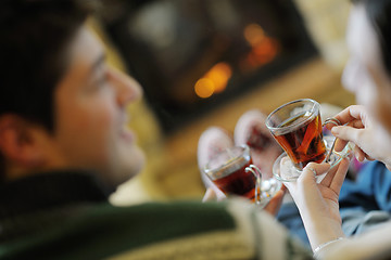 Image showing Young romantic couple sitting and relaxing in front of fireplace