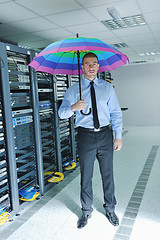 Image showing businessman hold umbrella in server room