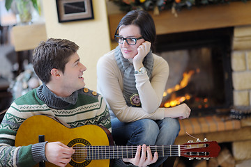 Image showing Young romantic couple sitting and relaxing in front of fireplace