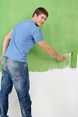 Image showing handsome young man paint white wall in color