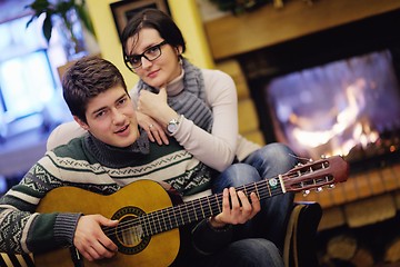 Image showing Young romantic couple relax on sofa in front of fireplace at hom