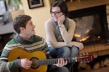 Image showing Young romantic couple sitting on sofa in front of fireplace at h