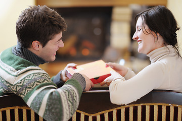 Image showing Young romantic couple sitting and relaxing in front of fireplace